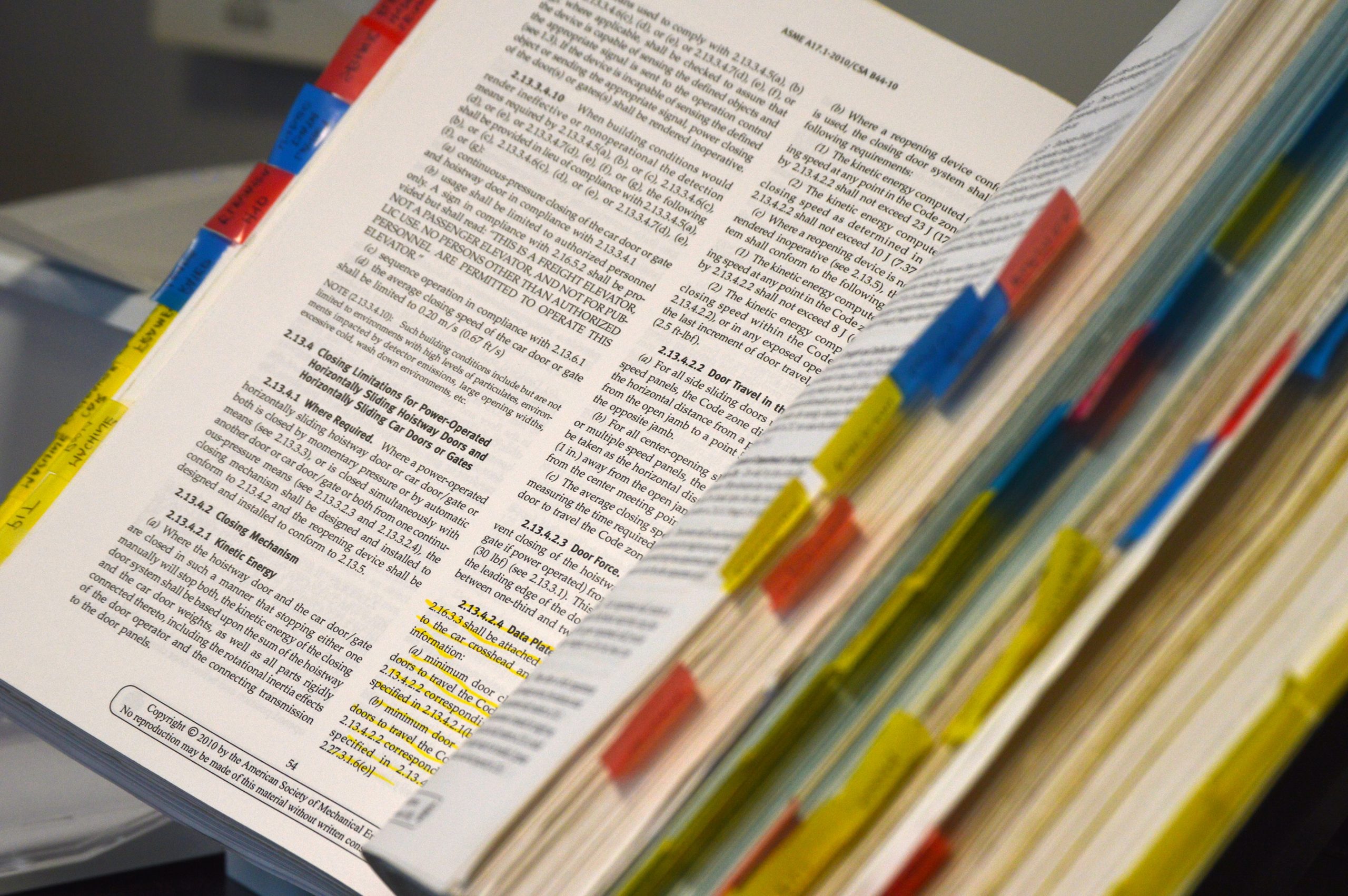 An open book with many colourful tags to mark pages