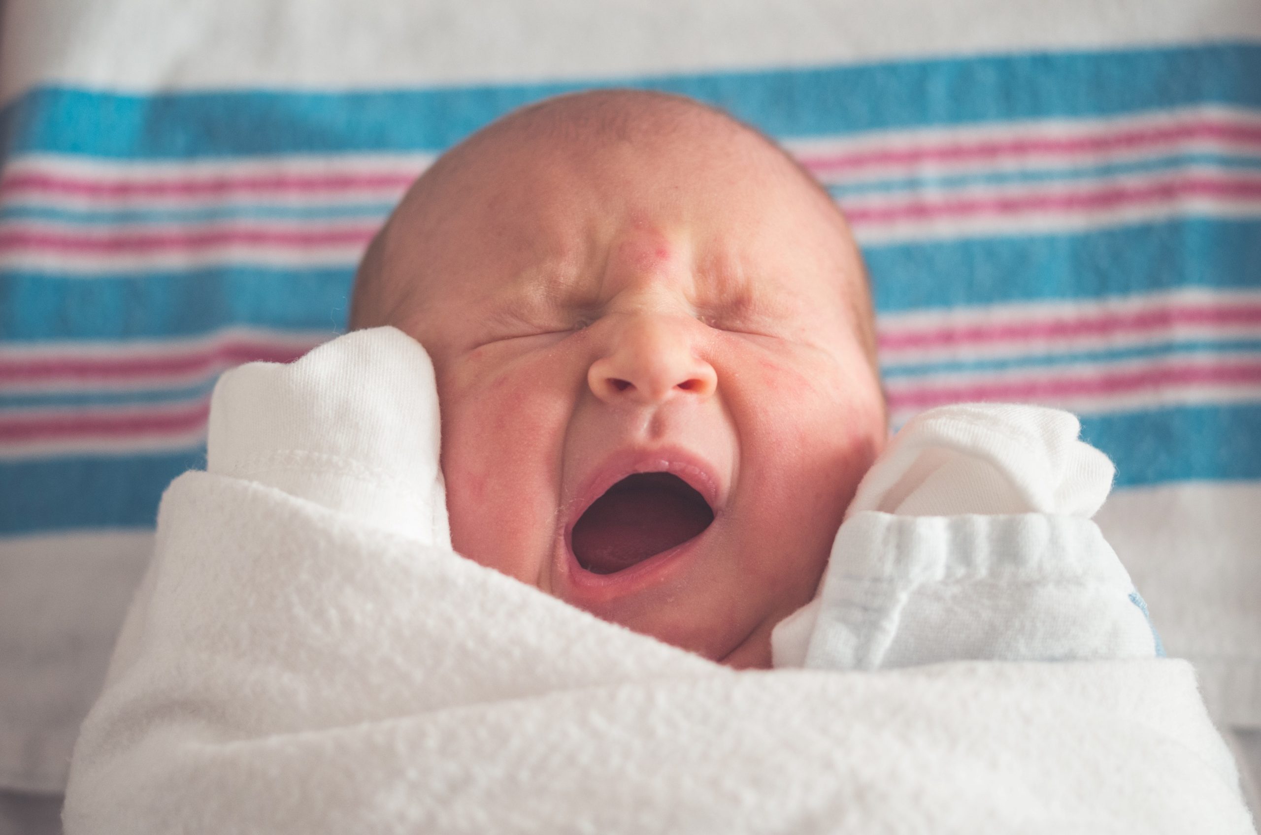 A swaddled, yawning baby. The image relates to fertility developments.